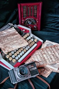 Camera in front of a typewriter and radio. 